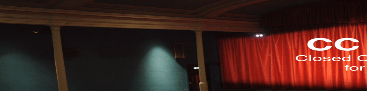 A theater interior. There are iphones at a few seats showing captions.